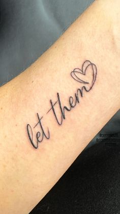 the word let them written in cursive writing on someone's arm with a heart