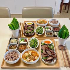 a wooden tray topped with bowls filled with different types of food and veggies