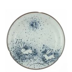 a blue and white plate with two rabbits flying in the sky on it's side