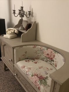 an old dresser with flowers on it and candles in the corner, next to a phone