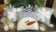 two snowman pillows sitting on top of hay next to a potted christmas tree