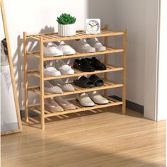 a wooden shoe rack with several pairs of shoes on it next to a clock and potted plant