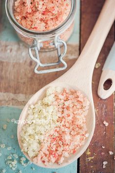 a wooden spoon filled with pink and white sprinkles on top of a table