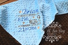 a blue baby blanket with the birth date printed on it and two matching bibs