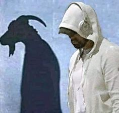 a man with headphones standing in front of a shadow of a goat on the wall