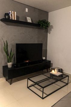 a living room with a television, coffee table and plant