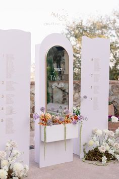 there is a table with flowers on it and two white pillars that have writing on them