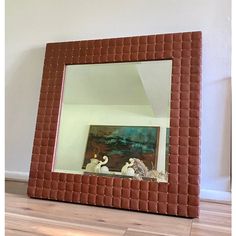 a mirror that is sitting on the floor in front of a wall with a painting