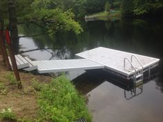 a dock sits in the middle of a body of water with trees and bushes around it