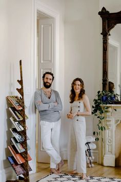 a man and woman standing next to each other in front of a mirror on the wall