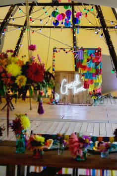 the inside of a marquee decorated with flowers and lights