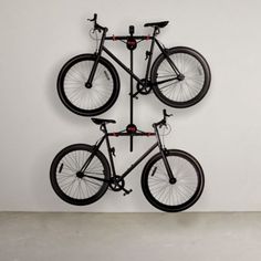 three bikes mounted to the wall with one bicycle on it's back and another bike on top