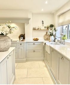 a large kitchen with marble counter tops and white cabinets, along with vases filled with flowers