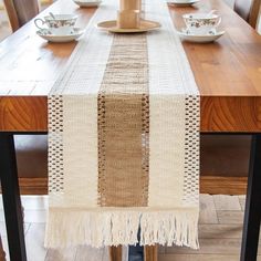 a wooden table topped with a white and brown striped table runner on top of a wooden dining room table