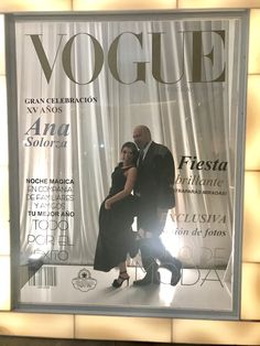 a man and woman are standing in front of a magazine cover that reads voge