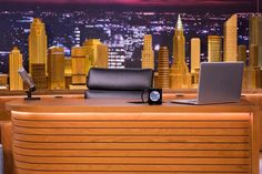 a desk with a laptop on it and a microphone in front of a cityscape