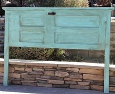 an old blue cabinet sitting on top of a stone wall