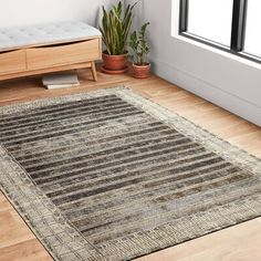 a living room area with hardwood floors and a rug on the floor that has stripes in it