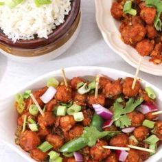 two bowls filled with meat and veggies next to rice on a white table