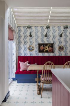 a dining room with red and blue booths, white walls and patterned wallpaper on the ceiling