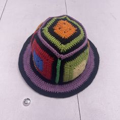 a multicolored crocheted hat sits on the floor