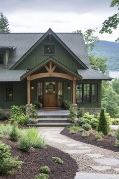 a green house with steps leading up to the front door and entry way, surrounded by greenery