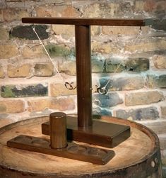 a wooden clock sitting on top of a tree stump in front of a brick wall