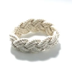 Imagine your visit to the beaches of New England.  This is the bracelet you see everywhere.  This bracelet is made from the classic cotton cord custom made to reflect the traditional rope used on our classic yachts.   Historically, these were given by sailors to their loves when they went on long voyages.  in the 1920's, the Newport Yachting Clubs were making these as a reward for a great season serving on their racing sailboats.  This traditional white cotton bracelet is 1 inch wide and comes in 3 sizes. Please let us know if you need a size not listed.  Stretch on over your hand, then get wet to shrink onto your wrist! Small - fits children and very fine framed women with a wrist size of 5 - 6 inches, inside circumference of 6 inches. Medium - fits women and teenagers with a wrist size o Handmade Nautical Style Bracelets For Beach, Handmade Nautical Bracelets For Beach, White Nautical Style Bracelet Gift, Sailors Knot Bracelet, Nautical Anchor Bracelets As Gift, Sailor Knot Bracelet, Adjustable Navy Nautical Bracelet, Sailor Bracelet, Cotton Bracelet