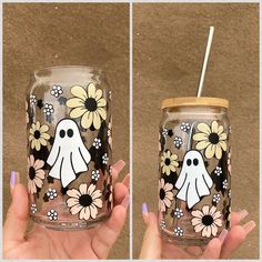 a hand holding a mason jar decorated with flowers and ghost