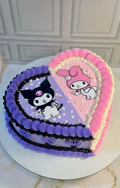 a heart shaped cake with hello kitty decorations on the front and sides, sitting on a table