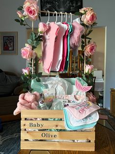 baby clothes and other items are on display in a living room with pink roses hanging from the ceiling