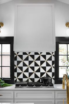 a kitchen with black and white tiles on the backsplash