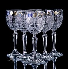 six wine glasses are lined up in a row on a black background with gold and silver decorations