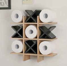 several rolls of toilet paper are stacked on wooden shelves in a room with white walls