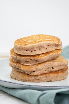 a stack of pancakes sitting on top of a white plate next to a blue napkin