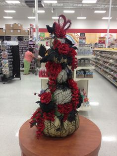 a display in a store with red and black flowers on the top of each vase