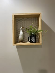 a wooden shelf with two vases and a bird figurine on it, hanging from the wall