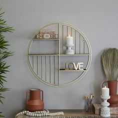 a table with vases, candles and other items on it in front of a gray wall