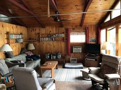 a living room filled with furniture and wooden walls