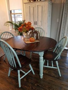 a dining room table with four chairs and a potted plant in the center on top