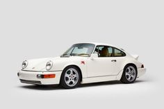 a white porsche parked in front of a gray background