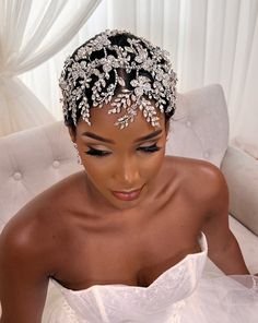 a woman in a wedding dress sitting on a couch wearing a bridal headpiece