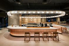 an empty restaurant with wooden chairs and counter tops in front of a circular light fixture