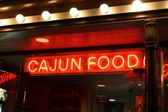 a neon sign that reads cajun food on the front of a building at night