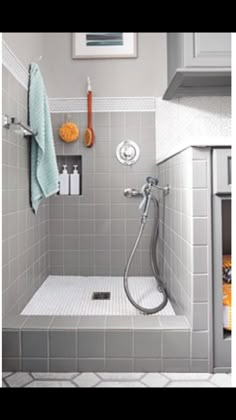 a bathroom with gray tiles and white fixtures, including a walk in shower that also has a built in shelf above the sink