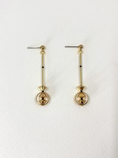 Minimalist and elegant, these linear dangle earrings feature unusual shapes and small details.  Golden brass elements are punctuated with tiny matte black beads to create a striking but understated design.  The elongated, clean lines ensure these earrings are sleek and modern.  Approximate measurements- 5.5cms long 1.25cms wide ✨All Set Theory jewellery comes with care instructions and a polishing pad to keep your jewels looking shiny and fabulous! ✨ Modern Gold-tone Linear Drop Earrings, Elegant Single Linear Brass Earring, Minimalist Brass Linear Long Drop Earrings, Long Drop Gold-tone Linear Earrings, Earrings Gold Long, Gold-tone Dangle Linear Earrings In Brass, Gold Long Earrings, Set Theory, Dangle Earrings Gold