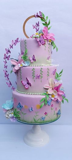 a three tiered cake decorated with flowers and butterflies