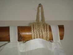 a piece of rope hanging from a wooden pole on top of a white cloth covered curtain