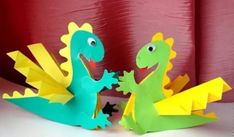 two paper dinosaurs are standing next to each other