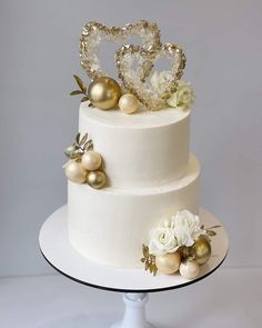 a three tiered white cake with gold decorations